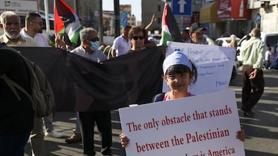 A Palestinian protester carries a placard during a demonstration in the occupied West Bank city of Ramallah as US President Joe Biden visited Israel. AFP