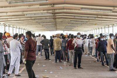 Men wait in line for their pre-check ahead of being tested for Covid-19. Antonie Robertson / The National