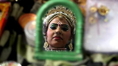 An artist from New Delhi looks at her reflection in a mirror, ahead of a performance of the religious observance of 'Mata Ka Jagran', at the end of the Navratri festival in Bhopal. Sanjeev Gupta / EPA