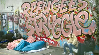 Migrants wait in the courtyard of a former high school before being evacuated by the police in Paris, France. Jacques Brinon / AP Photo