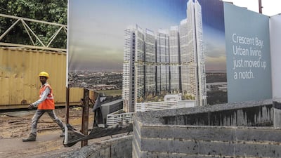 A worker walks past an advertisement for luxury residential towers at a construction site in Mumbai. Dhiraj Singh / Bloomberg News