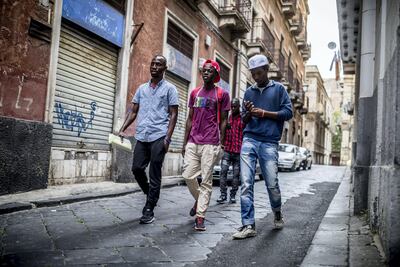 Refugees Mikailou Diallo (from left), Landing Solly Ameidou Sidy Iraore and Asowe Abdoulie walking through Catania in Sicily, Italy in May 2017, after leaving the community centre where social workers take care of the migrants and help them feel safe. Michael Kappeler. Picture-Alliance/DPA/AP Images
