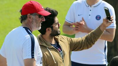 Paris Saint-Germain's French head coach Laurent Blanc (L) poses for a selfie with a fan during a training camp in the Qatari capital Doha, on December 28, 2015. AFP PHOTO / KARIM JAAFAR
