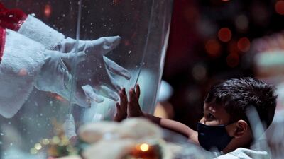 Abilio da Cruz Pinto, 77, dressed as a Santa Claus inside a plastic bubble, greets a child in a shopping mall in Brasilia, Brazil. Reuters