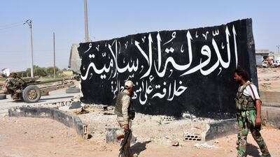 Syrian pro-government forces set up a road checkpoint next to a mural reading 'Islamic State' after they took control of the northern Syrian town of Maskanah from the jihadists in June 2017. AFP