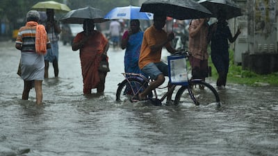 Pedestrians wade through flooded streets as the monsoon rain falls in Chennai. EPA