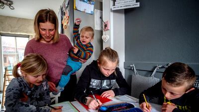 Katja helps her children with school work at home. One year into the coronavirus pandemic, she is still trying to keep her spirits up. AP Photo