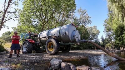 A farmer pumps water in a river near Wellin, southern Belgium. EPA