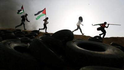 Palestinian protesters run during clashes with Israeli troops at Israel-Gaza border. Ibraheem Abu Mustafa / Reuters