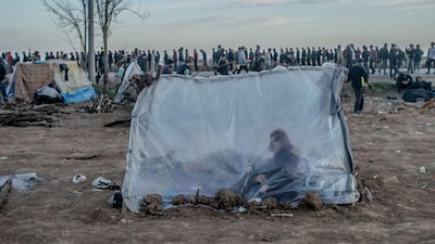 A Syrian woman sits in a tent with her son as others wait for food distribution in front of the Pazarkule border crossing to Greece, in Edirne. AFP