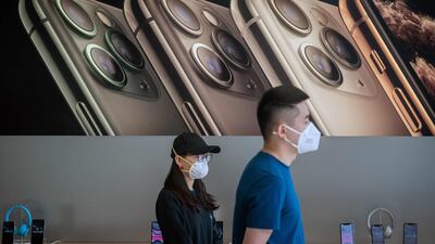 Apple staff wearing face masks as a preventive measure against coronavirus wait for customers at an Apple shop in Beijing. AFP