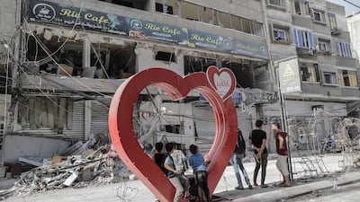Palestinian youth stand on a heart-shaped installation next to the rubble of a building following an Israeli airstrike on Khan Younis refugee camp, southern Gaza Strip,on Sunday. EPA