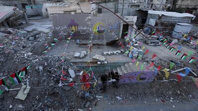 Palestinians gather near graffiti and the rubble of buildings in the southern Gaza Strip. Reuters