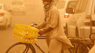 A Pakistani national covers his face with a head scarf while crossing the street in Dubai. Antonie Robertson / The National