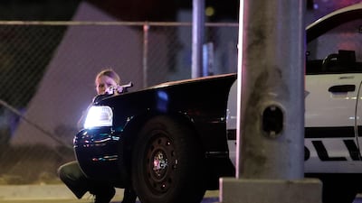 A police officer takes cover behind a police vehicle during a shooting near the Mandalay Bay resort and casino on the Las Vegas Strip. John Locher / AP Photo