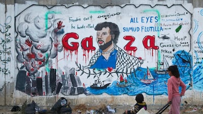 Palestinian children look at a mural depicting Israel's interception of ships participating in the Global Sumud Flotilla in Nuseirat, central Gaza. AFP