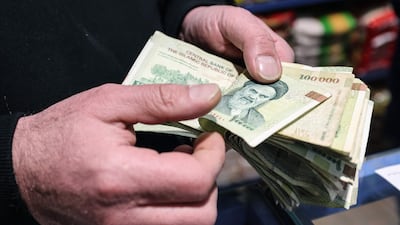A Tehran shop owner counts Iranian banknotes. The rial falling to a record low sparked protests in the capital. AFP