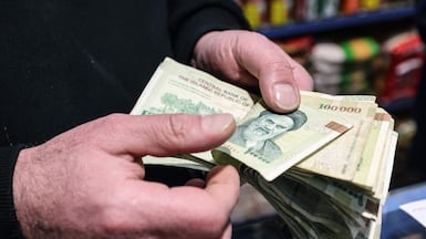 A Tehran shop owner counts Iranian banknotes. The rial falling to a record low sparked protests in the capital. AFP