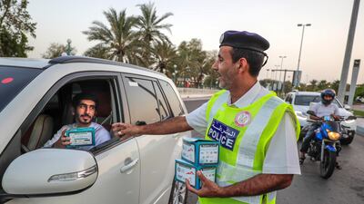 Red Crescent volunteers and Abu Dhabi Police distribute food to motorists during iftar at the corner of 11th Street and 18th. Victor Besa / The National