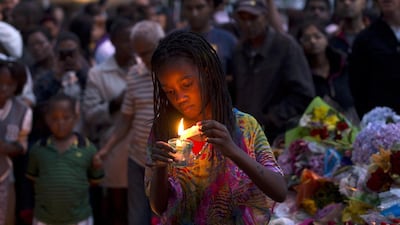 A girl lights a candle for South African former president Nelson Mandela at a wall of flowers laid by mourners outside Mandela’s home in Houghton, Johannesburg. Pedro Ugarte / AFP Photo