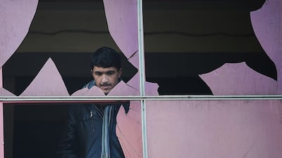 A man looks through a broken window at the site of a suicide attack in Kabul. January 26, 2014. Shah Marai / AFP