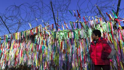 A woman walks past a military fence covered with ribbons calling for peace and reunification at the Imjingak peace park near the demilitarised zone dividing the two Koreas in the border city of Paju. AFP