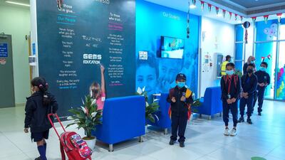Pupils wait for their turn to have their temperature checked at the lobby