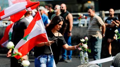 A Lebanese protester carries the national flag on the highway linking Beirut to north Lebanon, in Zouk Mikael a day after demonstrations swept through the eastern Mediterranean country in protest against dire economic conditions. AFP