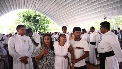 A woman is helped to walk as she cries during funeral. aFP