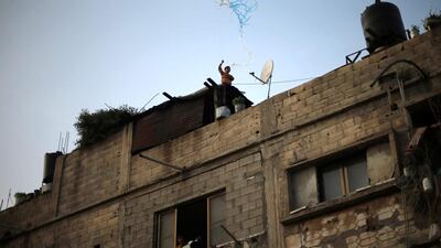A Palestinian boy looks out of a window as another flys a kite on the roof of their house in Beit Lahiya town in the northern Gaza Strip. Mohammed Salem / Reuters