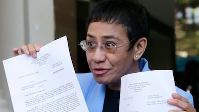 Maria Ressa holds up documents outside a courtroom after posting bail in one of the numerous legal cases brought against her. AP