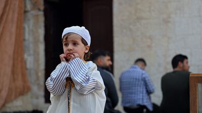 A Syrian child dressed in traditional Damascene dress stands as Muslims attend the prayers of Eid Al Fitr in Syria's rebel-held northwestern city of Idlib. AFP