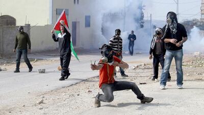 Palestinian protesters hurl stones during clashes over the Jewish settlement of Qadomem, near Nablus, in the West Bank on Friday. Five Palestinians were reportedly wounded during the clashes. Alaa Badarneh / EPA
