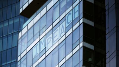Letters put up in the windows of an office block overlooking the stage where President Donald Trump will address the veterans’ day parade spell out “IMPEACH”. AFP