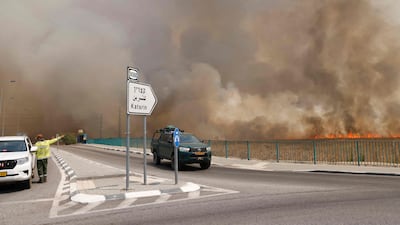 Vehicles leave an area engulfed by smoke from fires after rockets launched from southern Lebanon hit areas in the Israeli-occupied Golan Heights. AFP