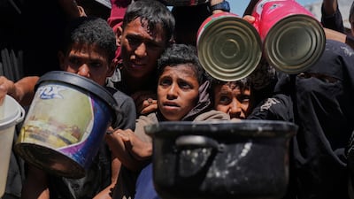 Palestinians jostle to receive rations at a charity kitchen in Khan Younis on Monday. AP