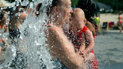 A mother and child cool off by walking through a park fountain in Antwerp, Belgium. AP