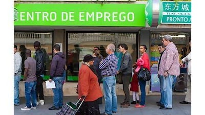A pedestrian wheels her shopping trolley past jobseekers queuing outside an employment centre in Sintra, Portugal. Mario Proenca / Bloomberg News