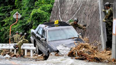 Japan Ground Self-Defense Force members search missing people near a damaged taxi after flooding caused by heavy rains hit Hiroshima, southwestern Japan, Thursday, on July 12, 2018. Kyodo News via AP