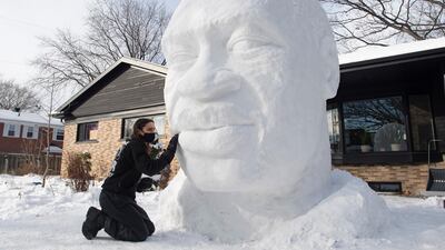 Timothee de Sandro puts the finishing touches on a snow sculpture of George Floyd in front of his house, Wednesday, Dec. 23, 2020 in Quebec City. De Sandro was shaken by the May, 2020 death of Floyd and wanted to pay tribute to him. (Jacques Boissinot/The Canadian Press via AP)