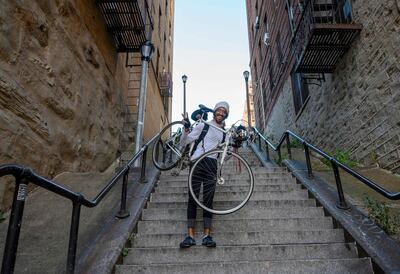Elliott Raylassi, a local resident since 2001, carries his bike up the staircase in the Bronx, made famous by the movie 'Joker'. AFP