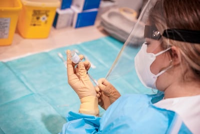 A health worker prepares a vaccine to be administrated to elderly patients. AP
