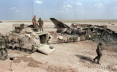 US soldiers at the Nasiriyah air base in Iraq, 300 kilometres south of Baghdad, beside a destroyed Mig jet. AFP
