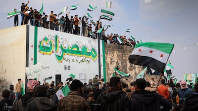 Syrians wave flags in the Idlib countryside to celebrate a year since Bashar Al Assad's downfall. Photo: Sana