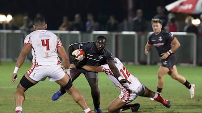 A Dubai Exiles player attempts to evade a tackle from an Abu Dhabi Harlequins opponent.