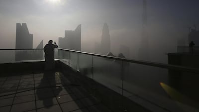 A man takes photos of the Burj Khalifa on a foggy day in Dubai. Kamran Jebreili / AP Photo