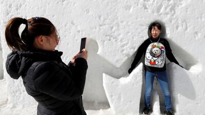 A woman takes a picture of her husband creating snow angels in Pyeongchang, South Korea. Eric Gaillard / Reuters