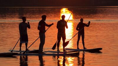 The sun rises behind stand-up paddlers at the river Alster in Hamburg, northern Germany. Christian Charisius / dpa via AP