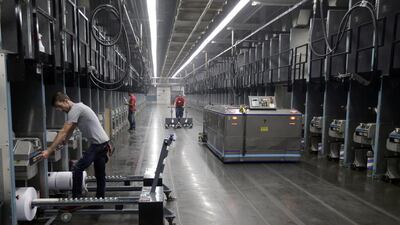 Workers exchange spools as a robot picks up thread made from recycled plastic bottles at the Repreve Bottle Processing Center, part of the Unifi textile company in North Carolina. America has lost more than 7 million factory jobs. Chuck Burton / AP