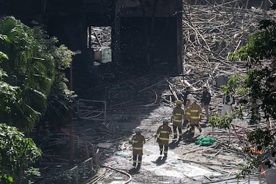 Firefighters walk through burnt buildings after the deadly fire at Wang Fuk Court, a residential estate in the Tai Po district of Hong Kong, on Saturday. AP